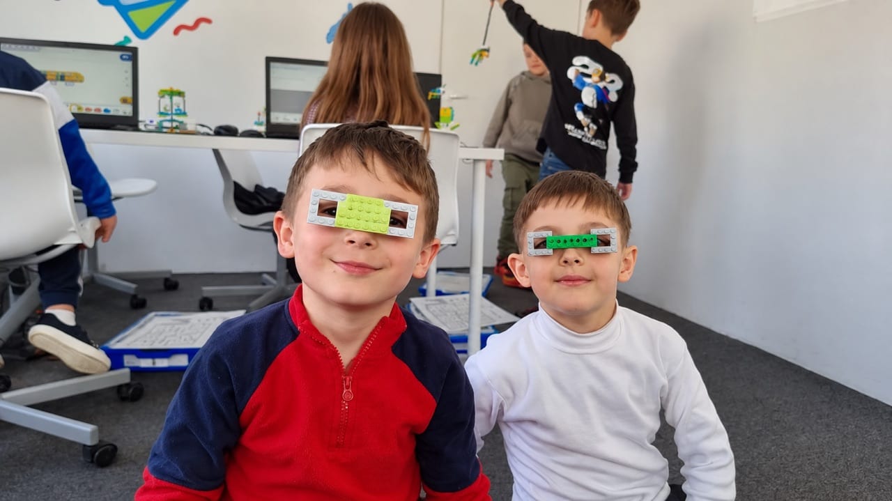 Doi copii de la cursul de Robotică LEGO Codeland, cu ochelari construiți din piese LEGO.